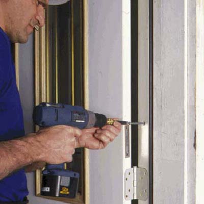 Swing open the door and drive long screws through the frame and into the original side jambs