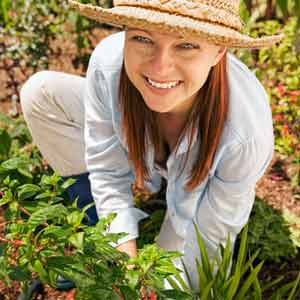 woman wearing wide brimmed hat while working in garden to protect skin from sun