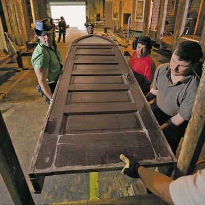 crew members hoist the chapel's front door into place