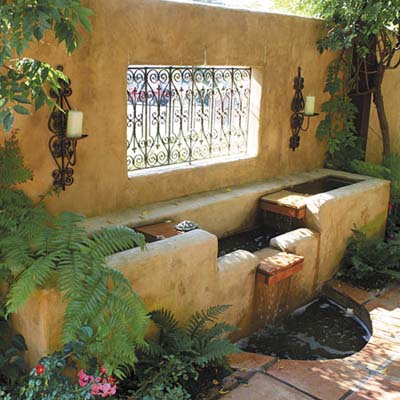 lovely fountain built into a masonry and ironwork divider 