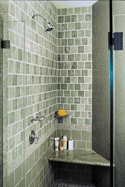 Shower has a curved wall and built-in seating and a glass door