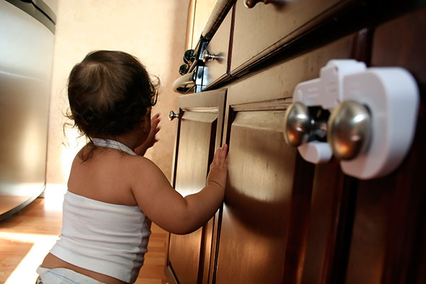 young child reaching up and over for a burner knob on top of a kitchen range