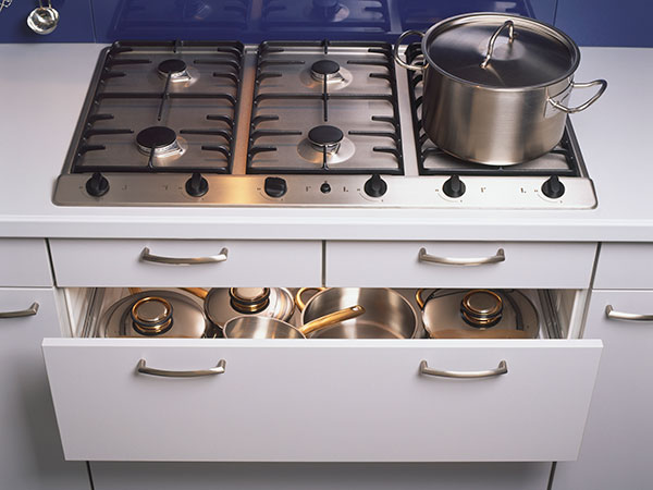 man pulling out a lower rack from a well organized kitchen cabinet