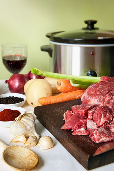 crock pot surrounded by different types of foods awaiting preperation