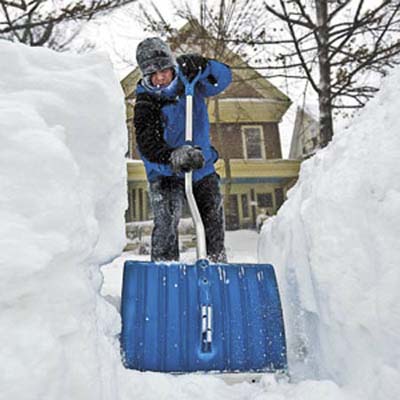 person shoveling a path through snow that reaches up to their shoulders