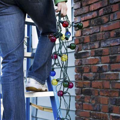 person standing on a ladder to hang christmas lights