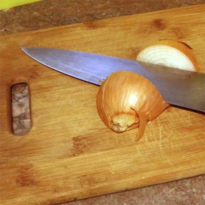 cutting board with knife resting between two halves of an onion