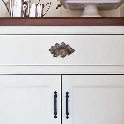 a cherry countertop and antiqued brass oak leaf and bar pulls give a custom look to the built-in hutch