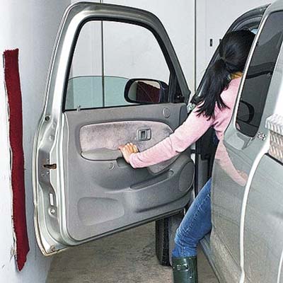 piece of carpet scrap mounted on garage wall to protect car doors from dings