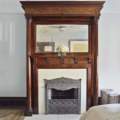 tall, built in mirror above decorative fireplace mantle in new york city house master bedroom