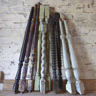 stack of salvaged wood spindles leaning against a brick wall