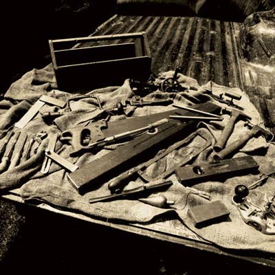 an array of antique tools, including antique hammers, chisels, hand planes, levels, compass, hand planes, and more