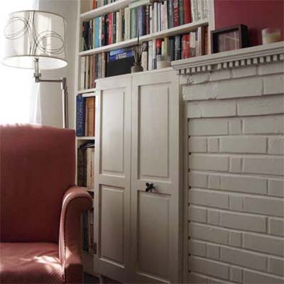 bookcases built into the space between mantel and window, with salvaged shutters as doors