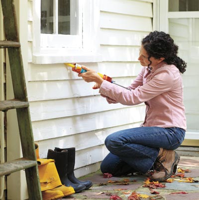woman caulking exterior of window for energy efficiency