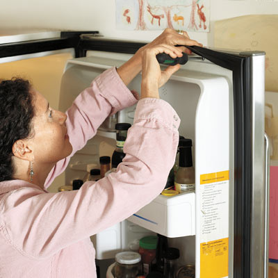 woman replacing gasket on refrigerator