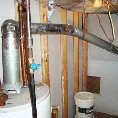 water heater exhaust pipe installed sloping downwards surrounded by exposed wood studs