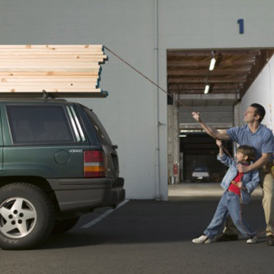 man and son lashing lumber to car