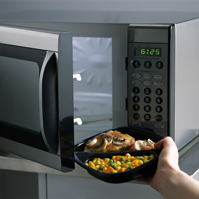 hand putting microwave dinner in oven