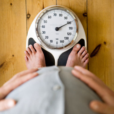 overweight man weighing himself on scale