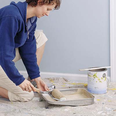 woman rolling paint in tin on drop cloth 