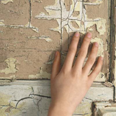 hand touching chipped painted wall