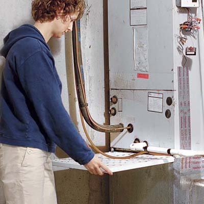 woman replacing furnace filter in basement