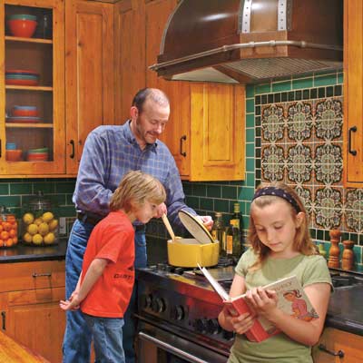 man and kids cooking in remodeled old world style kitchen with colorful tile backsplash