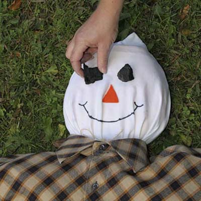 pieces of charcoal applied as eyes in a scarecrow's face