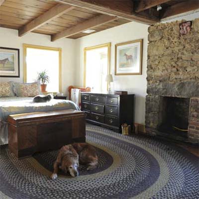 updated bedroom with wood ceiling and stone fireplace