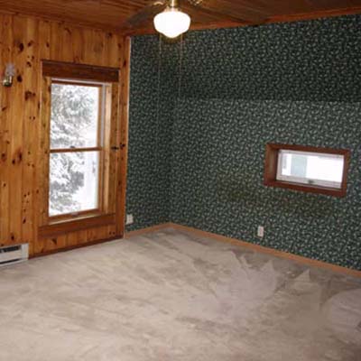 outdated bedroom with wooden walls and ceiling fan