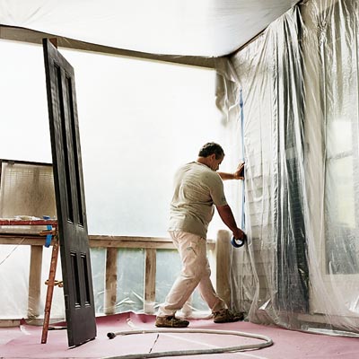 man installing plastic and drop cloths to prepare for spray painting