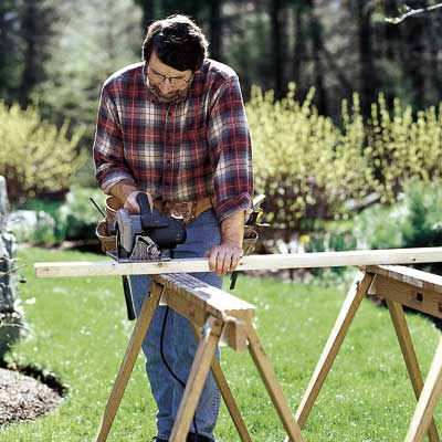 man using circular saw on saw horse