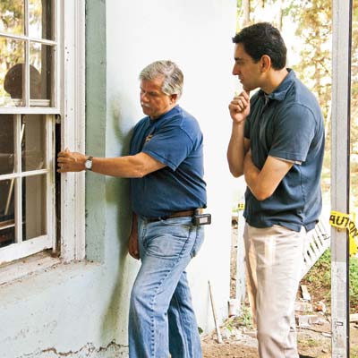 men checking exterior of window for lead paint
