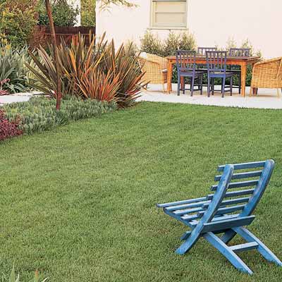 lush lawn with blue chair and dining patio in the distance