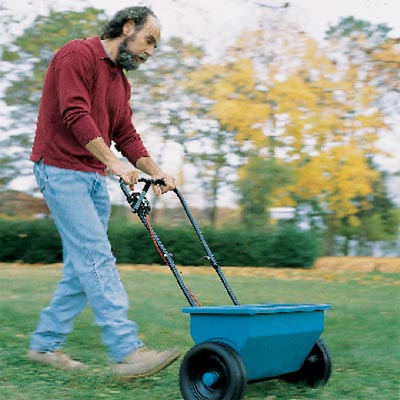 man spreading herbicides on lawn