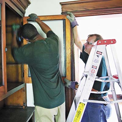crew members slicing through multiple coats of paint to remove built-in cabinetry