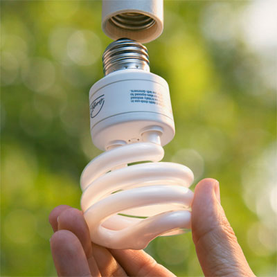 hand holding CFL near light fixture for efficient lighting