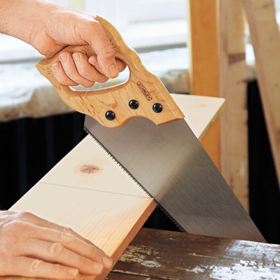 hands using handsaw on wood