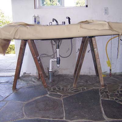 Kitchen made from sawhorses, plywood, pipes and tarp.