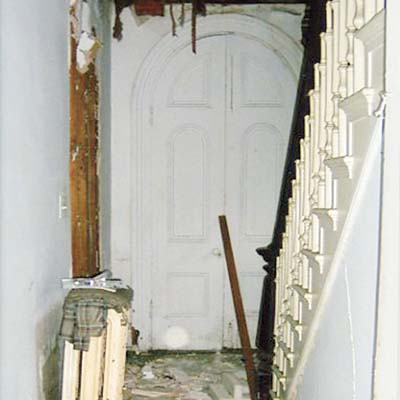 before photo of debris-strewn foyer with boarded up side entry