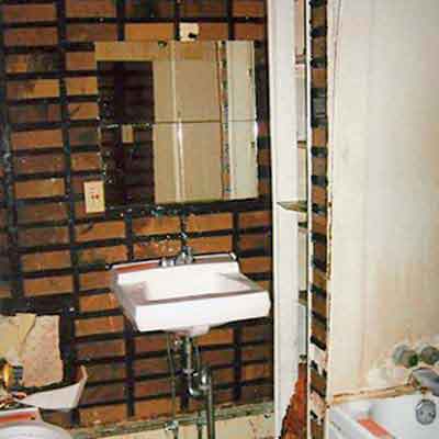 before photo of bath with multicolored tile and wall-mounted sink 