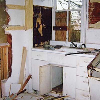 before photo of debris-filled kitchen with white metal cabinets 