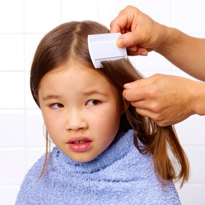 a woman combing a little girl's head for lice 