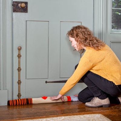 woman stuffing door jamb with old socks