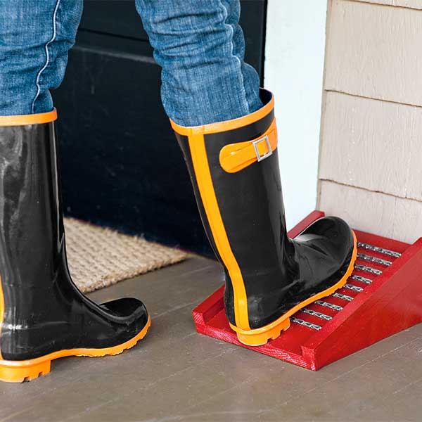 woman scraping her rain boots on boot scraper built with window sash chains