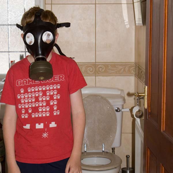young boy with gas mask on in smelly bathroom