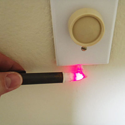 an electrical tester lit up under a dimmer switch
