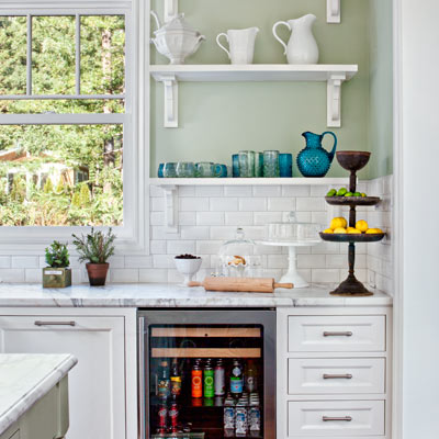 after kitchen remodel with open shelving across top of windows and along wall near sink, floor-level beverage fridge 