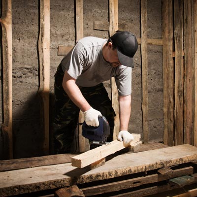 man cutting wood with saw 