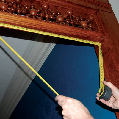 using tape measure to measure the top of a door frame